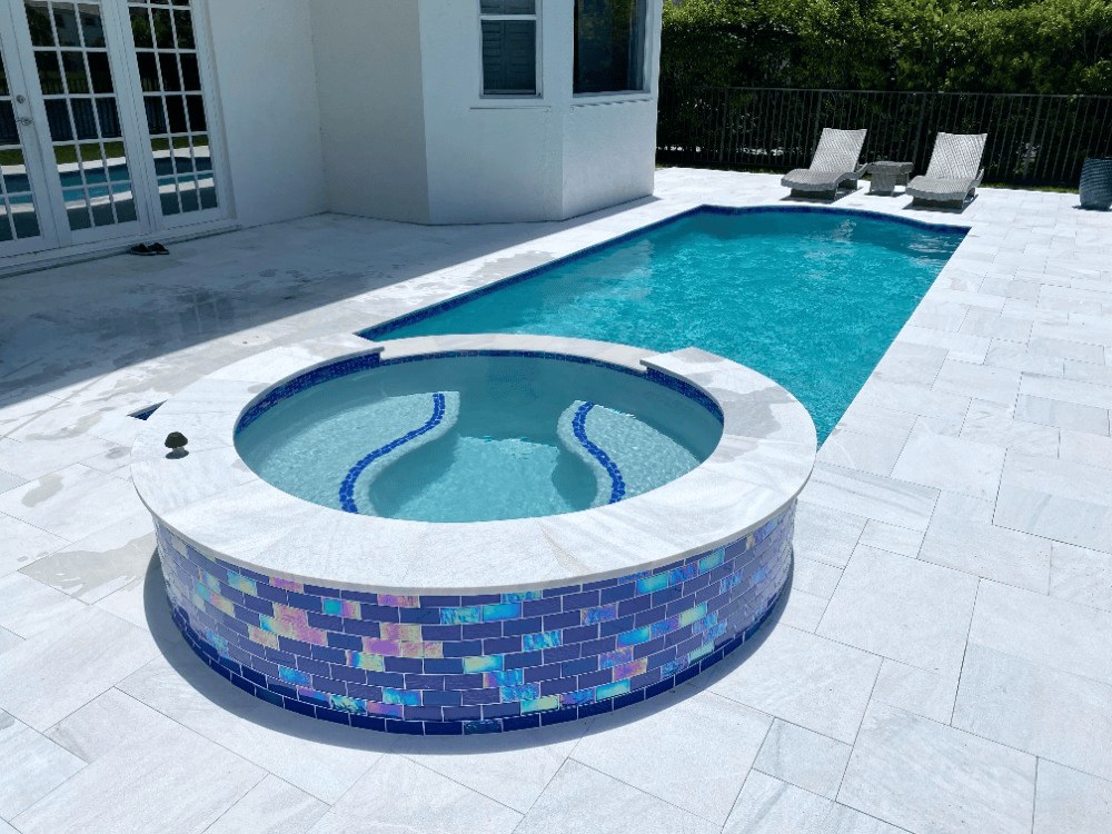 Remodeled pool and raised mosaic-tile spa with white paver deck